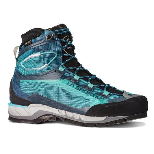 The La Sportiva Trango Tech GTX Women's is a teal and black, high-ankle mountaineering boot with thick tread, black toe cap, blue accents, and detailed lacing. Its rugged design and semi-automatic crampon compatibility suit technical mountain terrain.