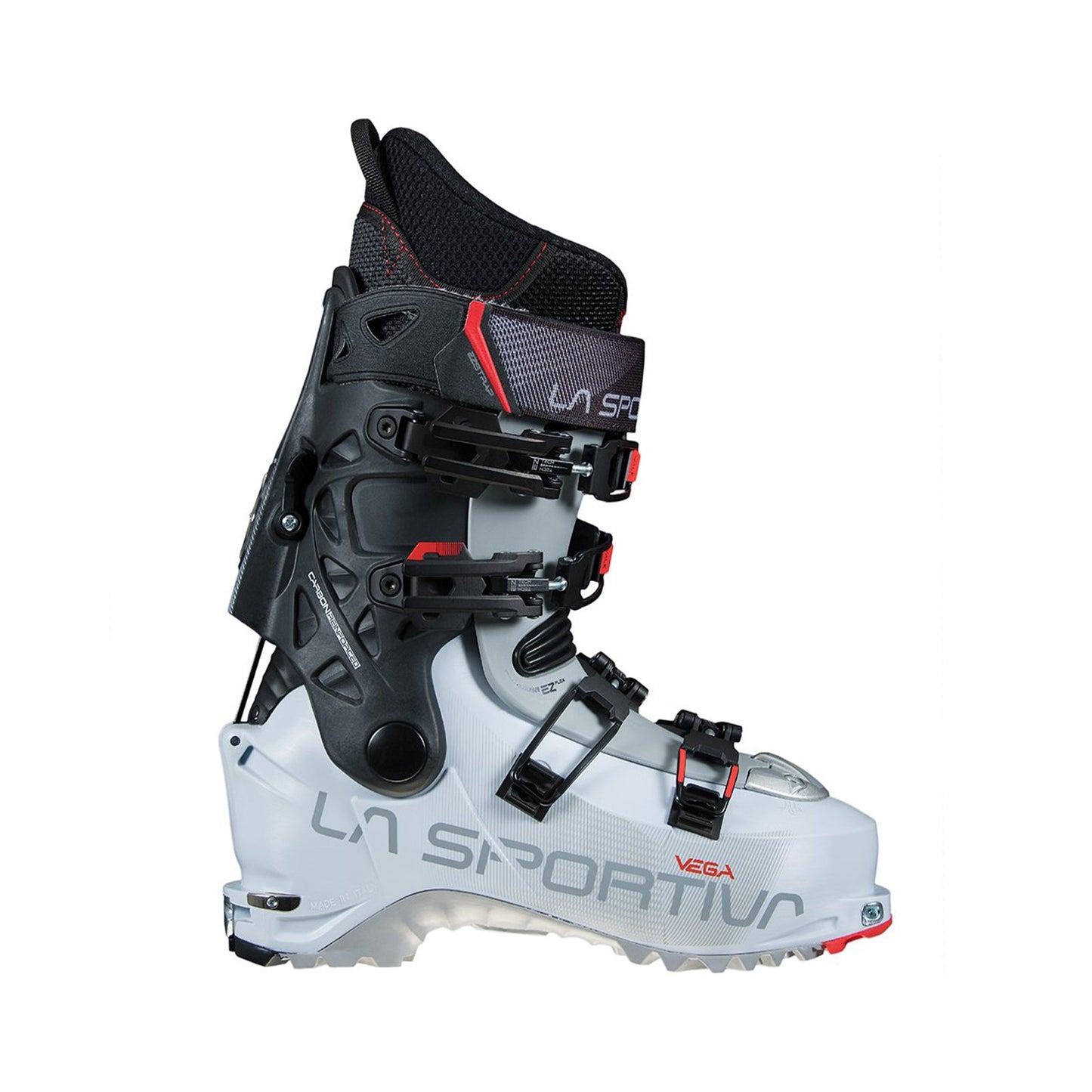 The Vega Women's by La Sportiva is a white and black ski boot with red accents, multiple buckles, and the brand name on the side. Shown upright in profile, this backcountry boot is designed for exceptional downhill performance.