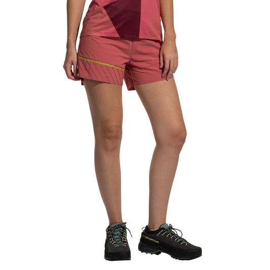 A person wearing La Sportiva Comp Shorts Women's (2025), durable black trail running shoes, and a pink and maroon athletic top stands with arms relaxed by their sides, shown from shoulders down against a white background.