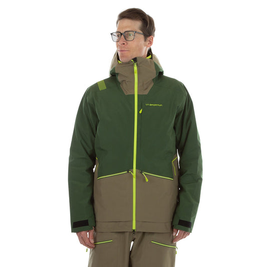 A man wearing glasses models the La Sportiva Chaser EVO Shell Jacket Men's, a two-tone green and brown outdoor jacket with yellow zippers, underarm ventilation, hood, and La Sportiva branding, against a plain white background.