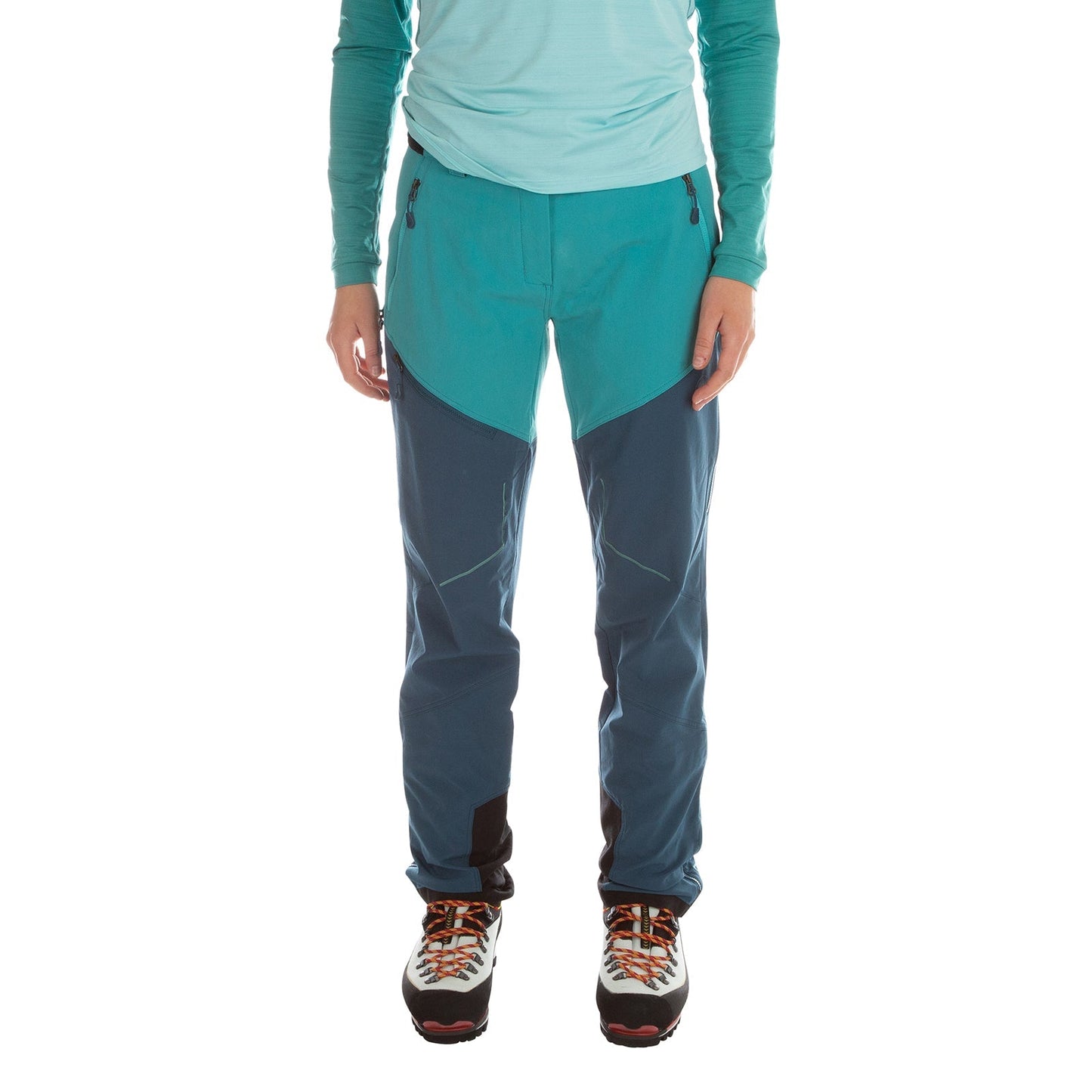 A person stands against a white background wearing La Sportiva Excelsior Pants Women's in turquoise and teal, a light blue long-sleeve top, and orange-laced hiking shoes. Face not visible. Ideal for ski-touring or mountaineering.
