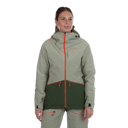 A woman with brown hair pulled back stands against a white background, wearing the La Sportiva Chaser EVO Shell Jacket Women's in light gray and dark green with orange zippers, reflective details, and underarm ventilation. She looks slightly to the side.