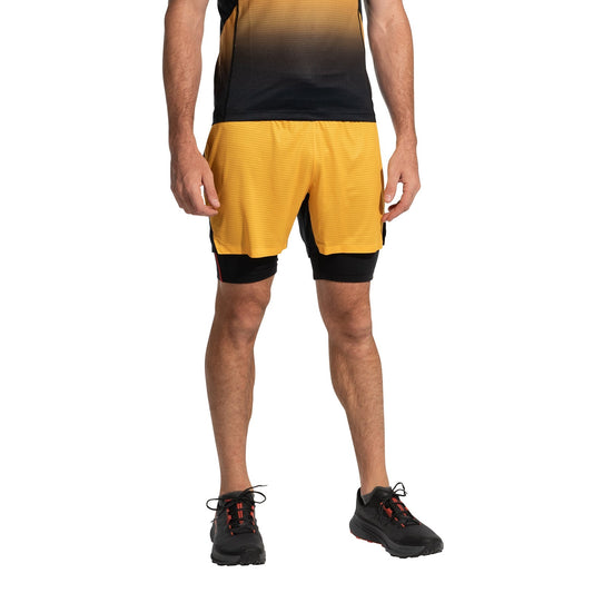 A man stands against a white background wearing a black and yellow gradient T-shirt, La Sportiva Ultra Distance Shorts Men's (2025) with black inner lining, and black running shoes with red accents.