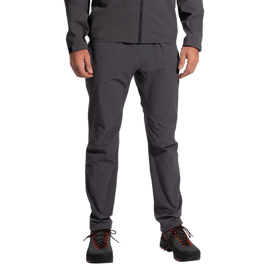 A person wearing La Sportiva Helixir Pants Men's (2025) in dark gray, featuring harness-compatible pockets, stands against a white background. The image is cropped from the shoulders down.