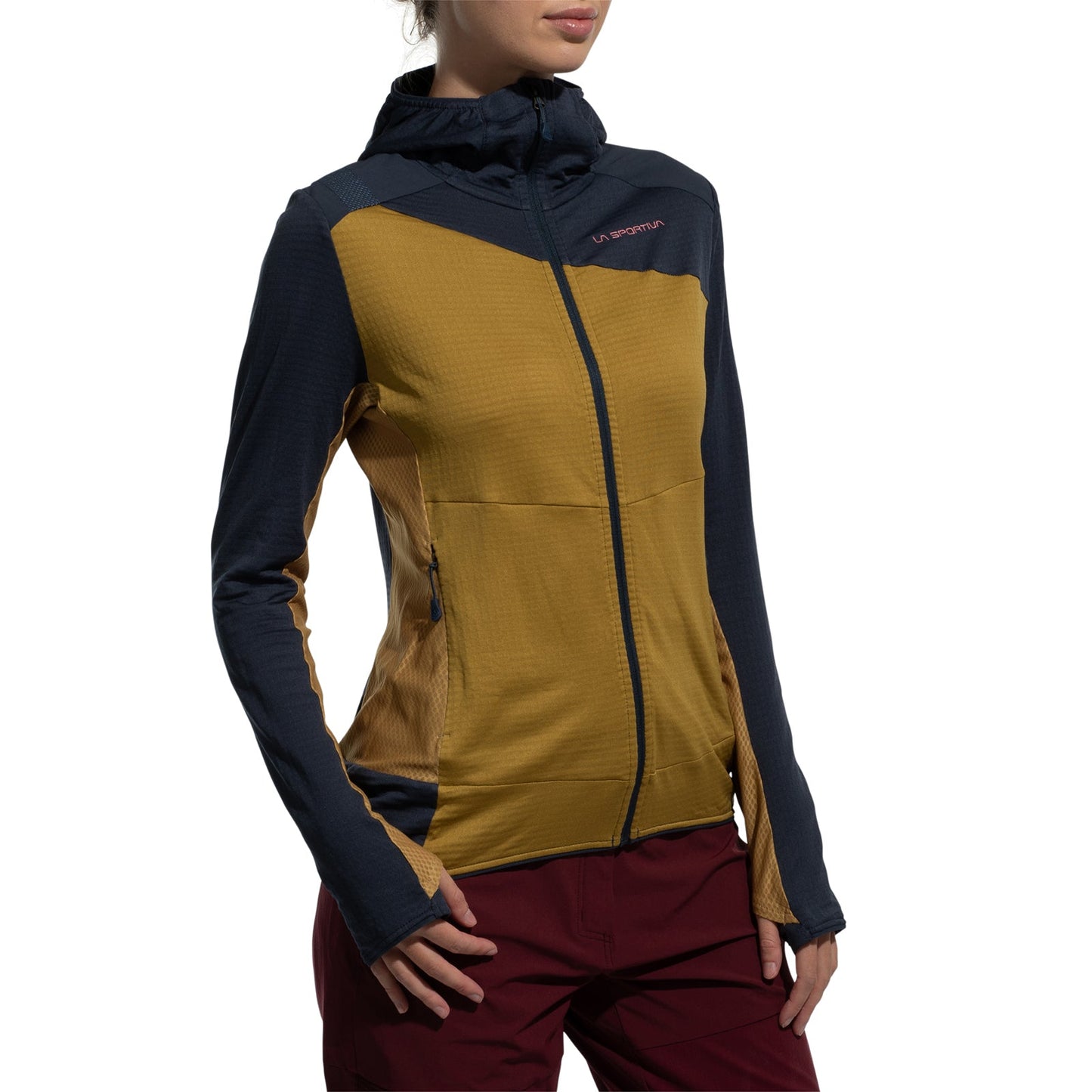A person wears the La Sportiva Aequilibrium Thermal Hoody Women's (2025), a color-block zip-up jacket with navy sleeves, mustard yellow panels, hood, and high collar, paired with maroon pants. The background is white.