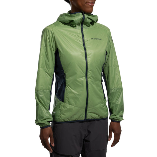 A person wears a La Sportiva Aequilibrium Lite Insulation Jacket Women's (2025) in light green with a hood, black trim, zippered pockets, subtle chest logo, and dark gray pants. The jacket offers breathable warmth for technical climbs. Face is partially out of frame.
