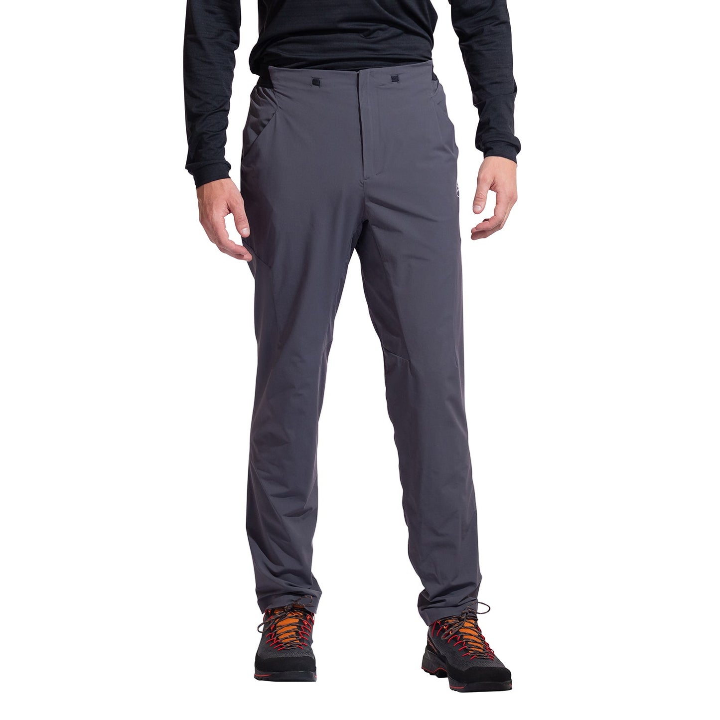A person wearing La Sportiva Trail Guard Pants Men's (2025) in dark gray stands with arms relaxed at their sides, paired with a black long-sleeve shirt and colorful hiking shoes against a white background.