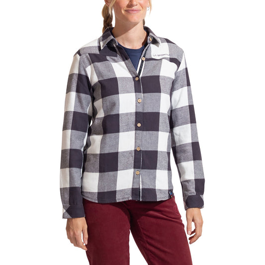 A woman wearing the La Sportiva Rambler Flannel Shirt in black and white plaid with coconut buttons and a small logo on the left chest, paired with maroon pants, stands against a white background.