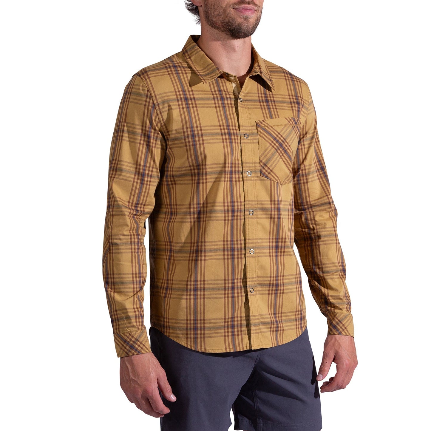 A man wearing the La Sportiva Outer Space Long Sleeve Shirt Men's in yellow-brown plaid, featuring a chest pocket and reinforced elbows, stands with relaxed arms by his sides, paired with dark shorts.