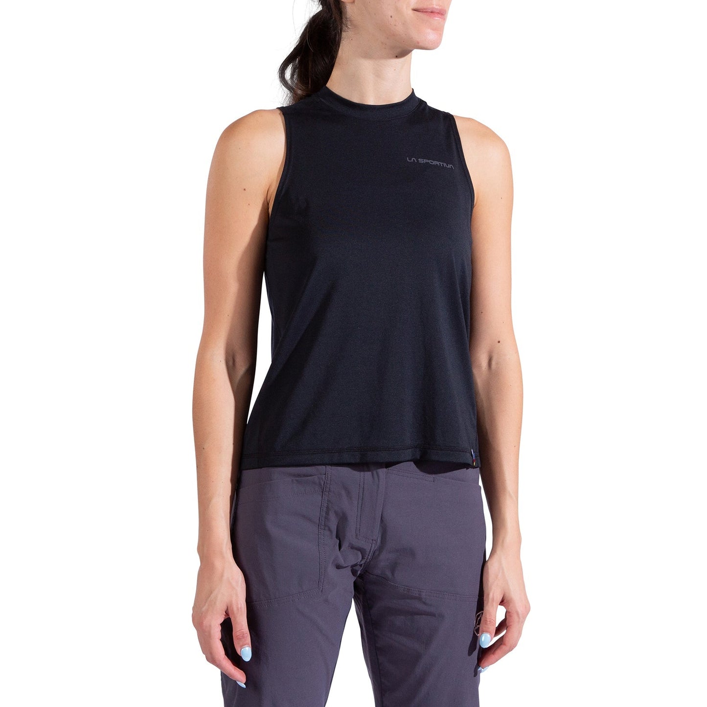 A woman models the La Sportiva Just Right Tank Women's in black with gray pants, standing against a white background, turned slightly to the side with her hands relaxed at her sides.