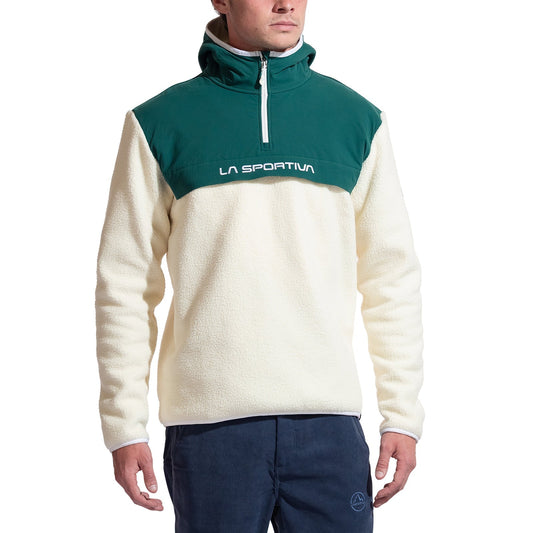 A person wears the La Sportiva Guidance Sherpa Hoody Men's, a cream-colored recycled fleece with a green top section, high collar, and LA SPORTIVA logo across the chest, paired with blue pants.