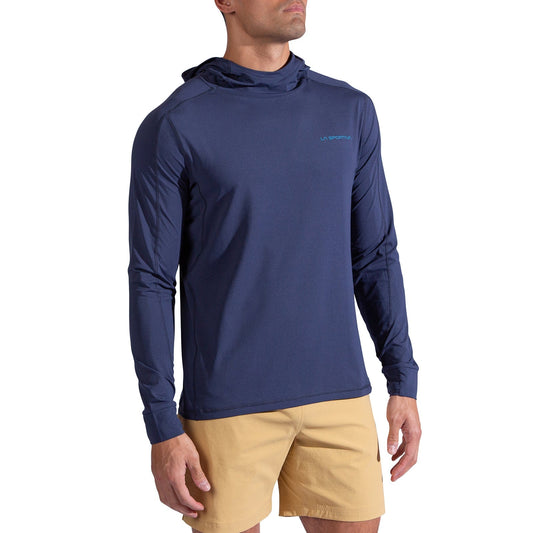 A man wearing the La Sportiva Cloud Shadow Sun Hoody (men's, lightweight, UPF 50+, navy blue) and tan shorts stands against a plain white background.