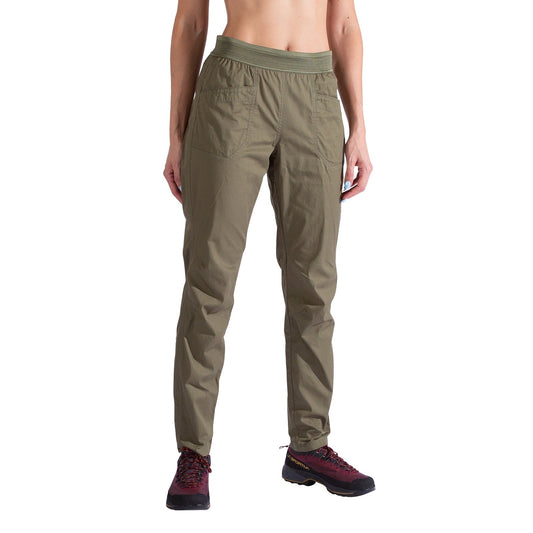 A person wearing La Sportiva Roots Pants Women's in olive green with articulated knees, elastic waistband, and front pockets, along with maroon hiking shoes, stands against a white background.