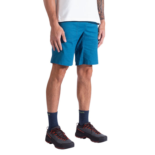 A person is shown from shoulders to feet, standing against a white background, wearing La Sportiva Bolt Shorts Men's paired with a white t-shirt, dark socks, and black hiking shoes with red laces.