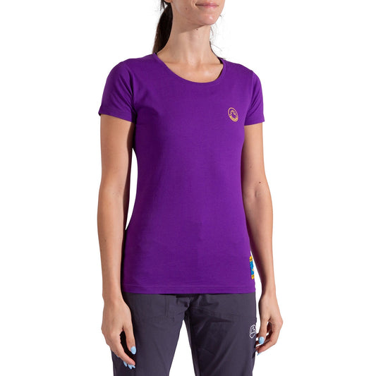 A woman in the La Sportiva Climbing on the Moon T-Shirt Women's—fitted, short-sleeved, purple with a small chest logo—and dark pants stands against a white background. Her face is partially out of frame.