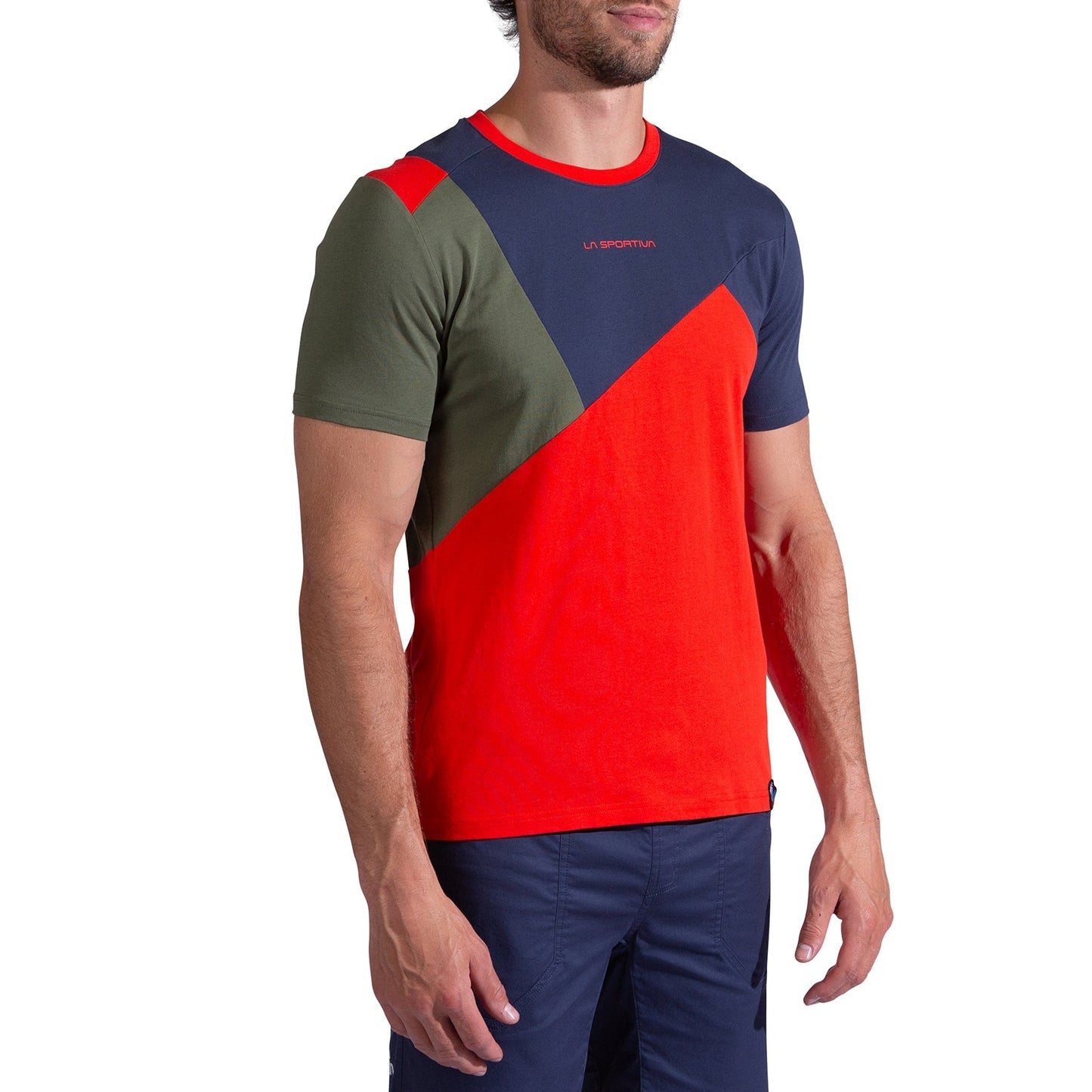 A man in a La Sportiva Dude T-Shirt Men's with red, navy blue, and olive green color blocks and navy blue shorts stands against a white background.