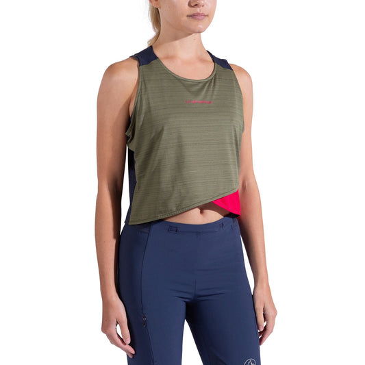 A woman wearing the La Sportiva Sunfire Tank Women's, an olive green asymmetrical quick-drying crop top, paired with navy blue athletic leggings and standing against a white background.