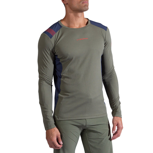 A man wearing the La Sportiva Beyond Long Sleeve Men's top in olive green with navy and maroon accents, paired with matching olive green Polartec Delta pants, stands against a white background.