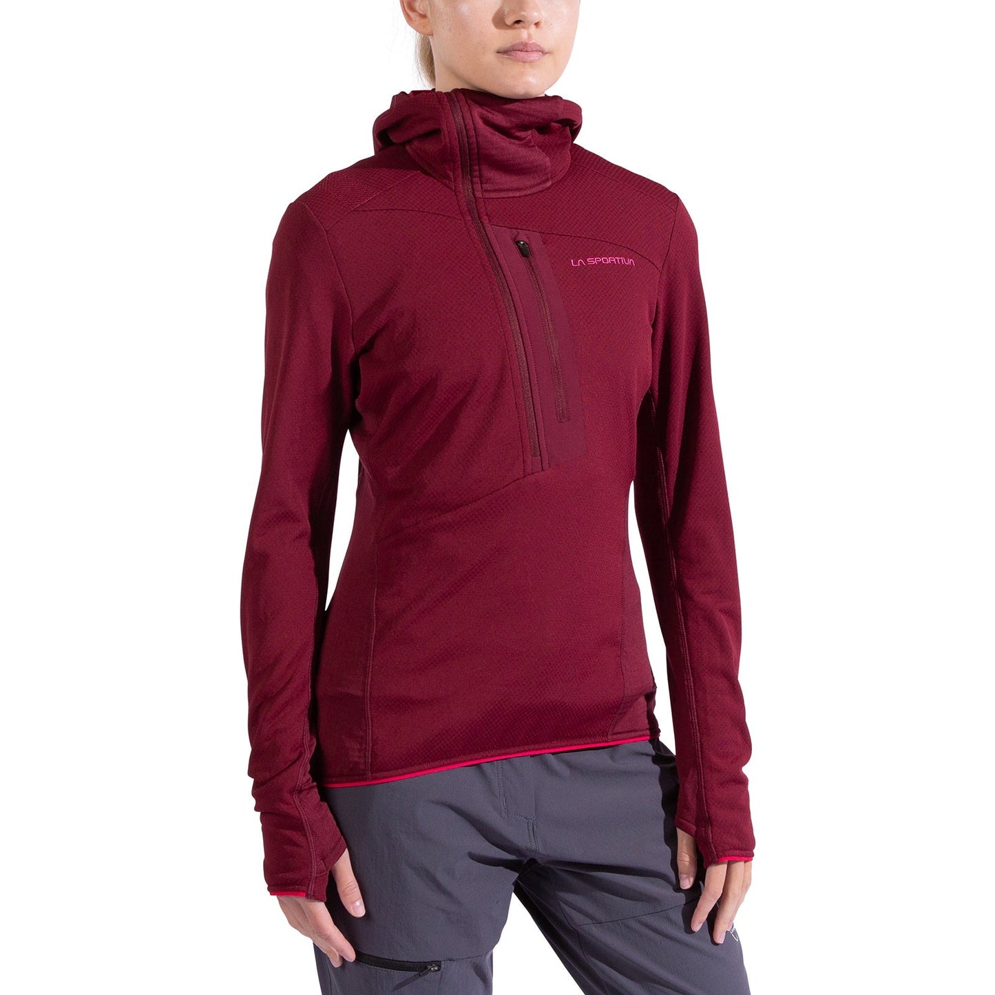 A person wears the La Sportiva Big Wall Pullover Hoody Women's—a fitted, long-sleeve maroon climbing hoody with TechStretch Aero Fabric, Polartec inserts, high neck, thumb holes, zippered chest pocket, and logo—against a white background.