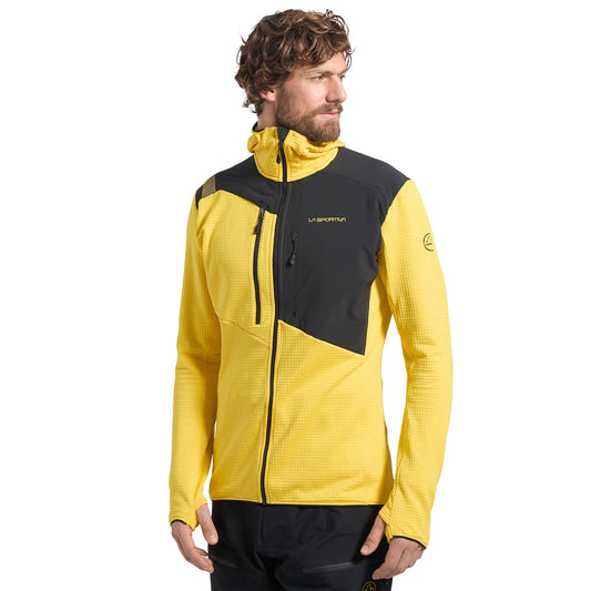 A man wears the La Sportiva Lucendro Thermal Hoody Men's, a yellow and black high-collar zip-up ideal as a thermal layer for mountaineers, while looking to his left against a plain white background.