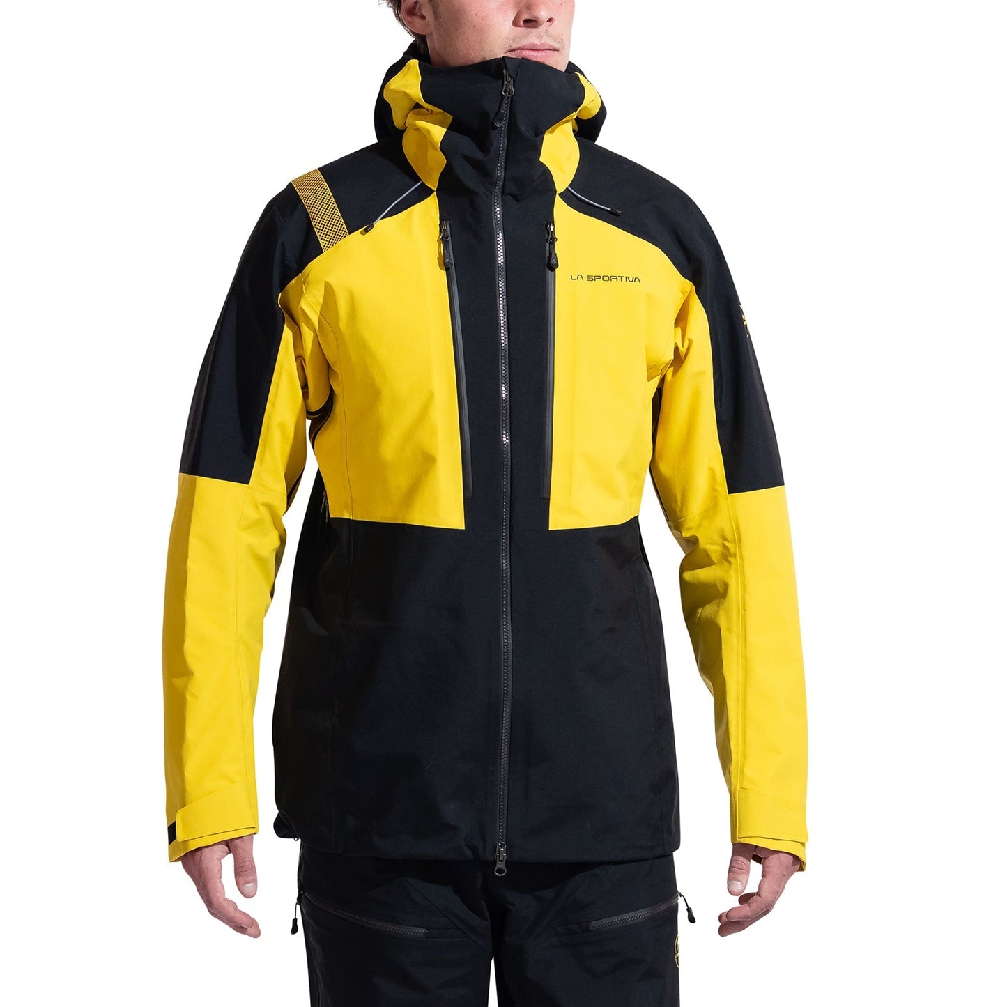 A person wearing a La Sportiva Supercouloir GTX Pro Jacket Men's, a yellow and black GORE-TEX PRO mountaineering hardshell with zippered pockets, stands with arms relaxed at their sides against a white background.