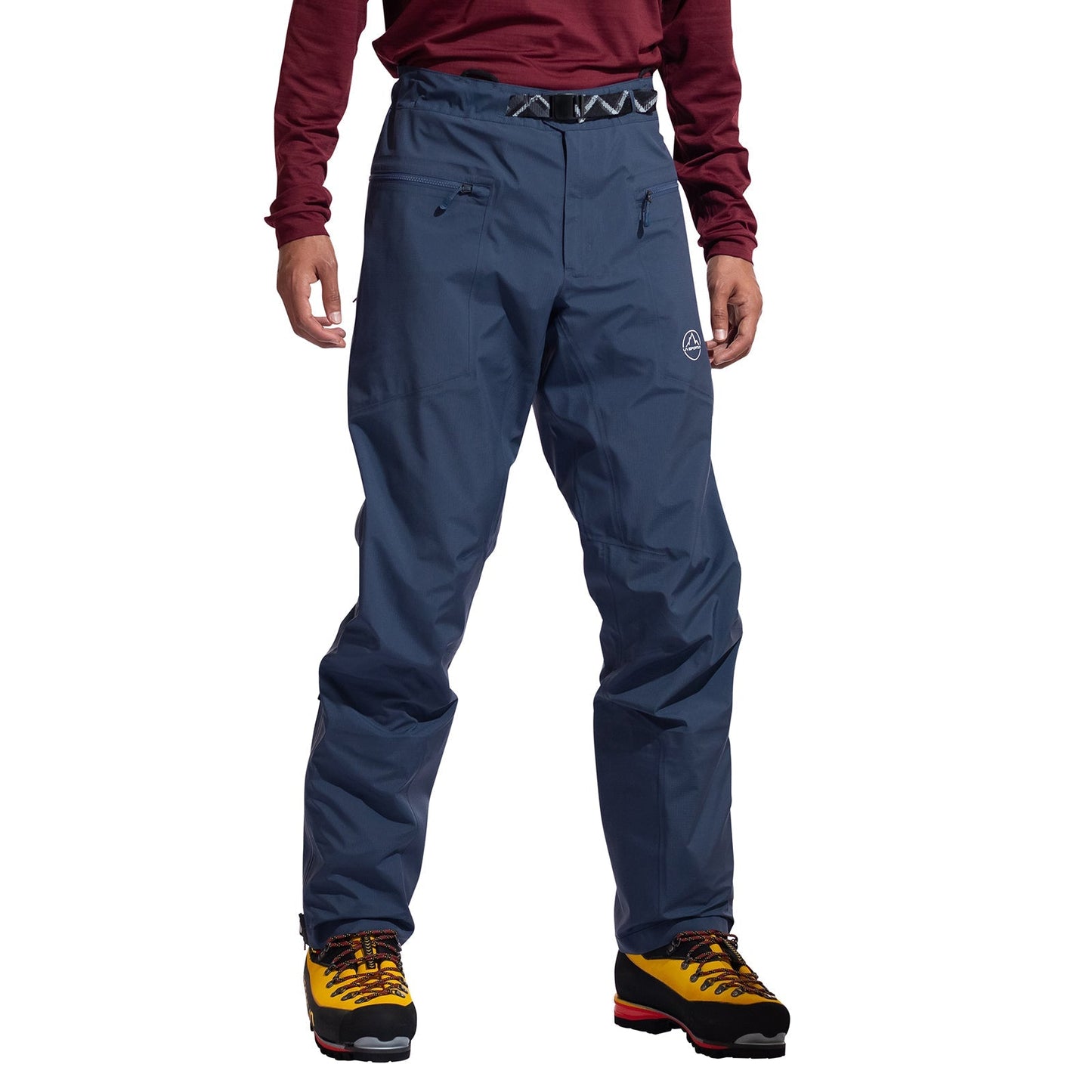A person wearing La Sportiva Alpine Guide GTX Performance Pants Men's—waterproof, breathable pants with zippered pockets—is shown from the waist down, paired with yellow hiking boots, against a white background.