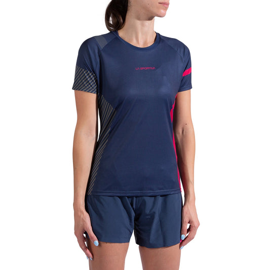 A woman in a La Sportiva Flow T-Shirt Women's, navy blue with subtle stripes and a red La Sportiva logo on the chest, and matching shorts stands against a white background.