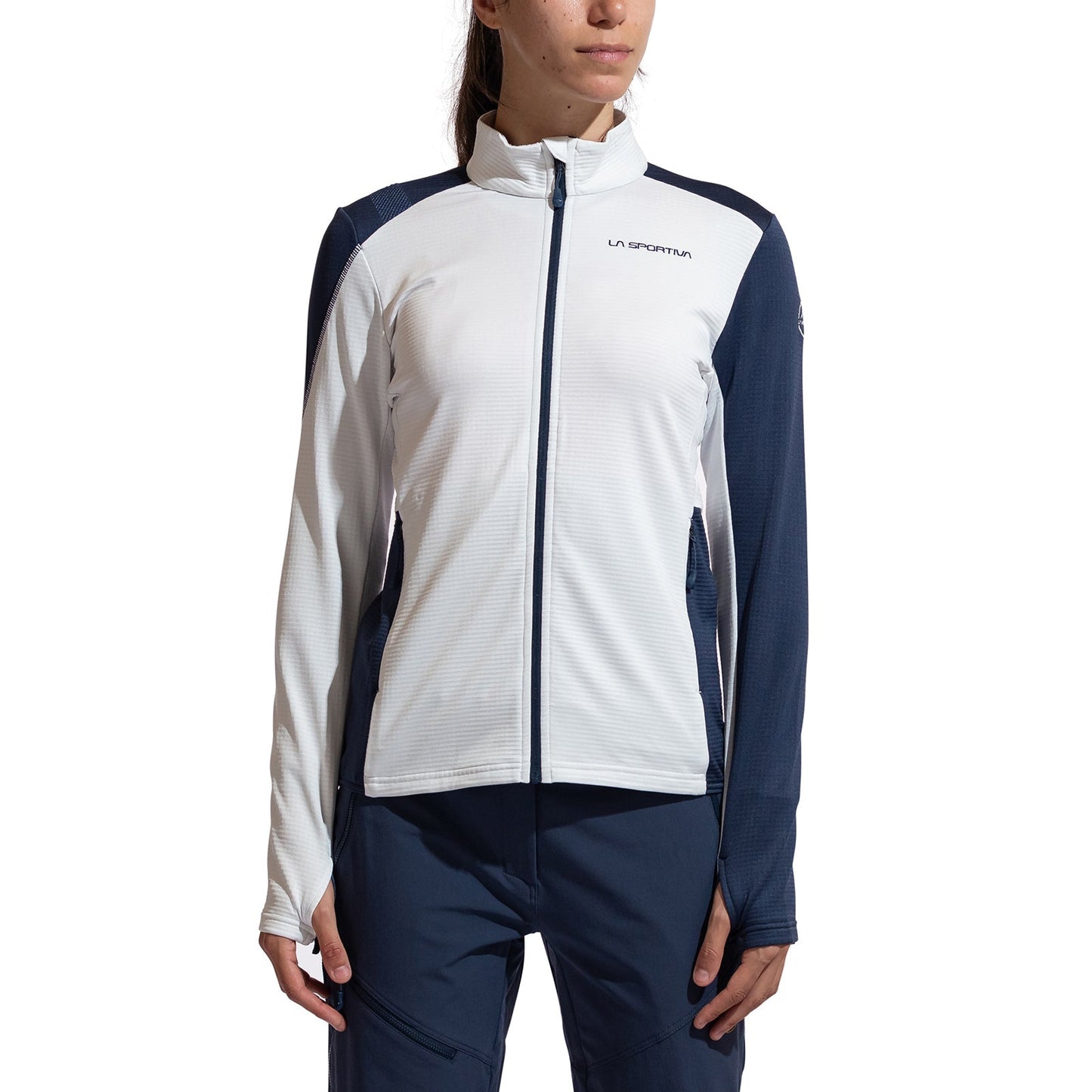 A woman wearing a La Sportiva Chill Thermal Jacket Women's in white and navy with a front zipper, long sleeves, and matching navy pants, standing against a plain white background.