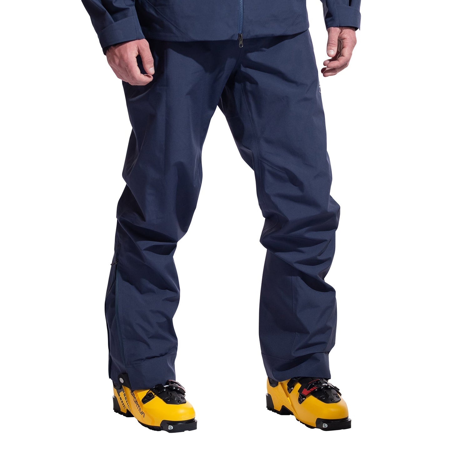 A person in La Sportiva Crest Evo Shell Pants Men's, dark blue in color, paired with bright yellow ski boots is shown from the waist down against a plain white background.