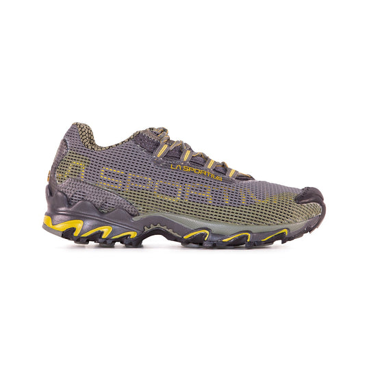 The La Sportiva Wildcat is a single olive green and black running shoe with yellow accents, mesh upper, thick textured sole, and La Sportiva logo. Photographed in profile on a white background, it’s perfect for long trail adventures.
