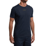 A man wears a navy blue, short-sleeve La Sportiva Dude T-Shirt Men's (2025) with matching shorts. The shirt has small yellow LA SPORTIVA text on the chest. His head is not visible in the image.