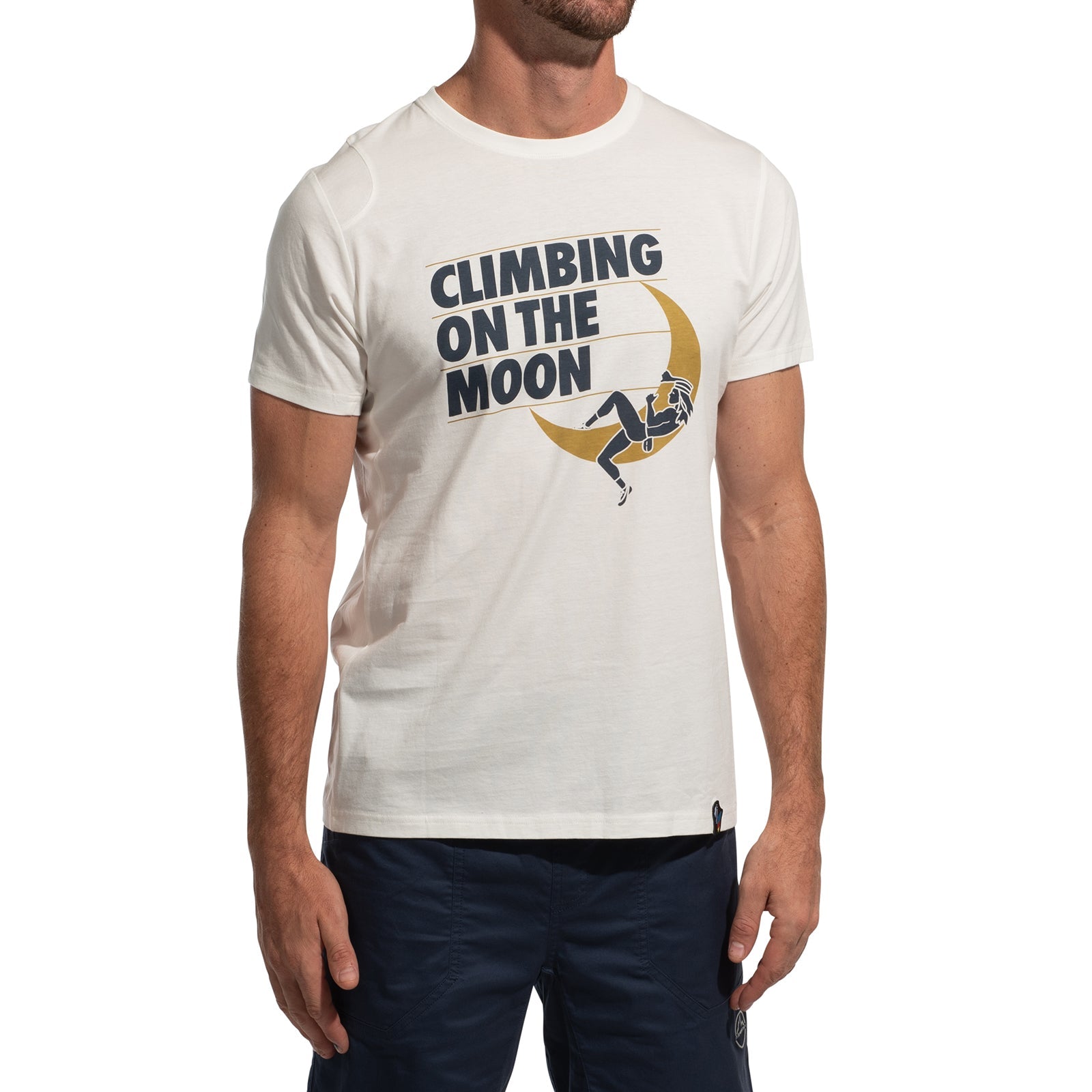 A man wears the La Sportiva Moon Rock T-Shirt Men's (2025) featuring "CLIMBING ON THE MOON" text and a graphic of a person climbing a yellow crescent moon, paired with dark blue shorts against a white background.
