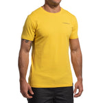 A man in a bright yellow La Sportiva Dawn Wall T-Shirt Men's with a left chest logo pairs it with black shorts. His head isn't visible, enhancing the adventurous, ascent-inspired vibe of the image.