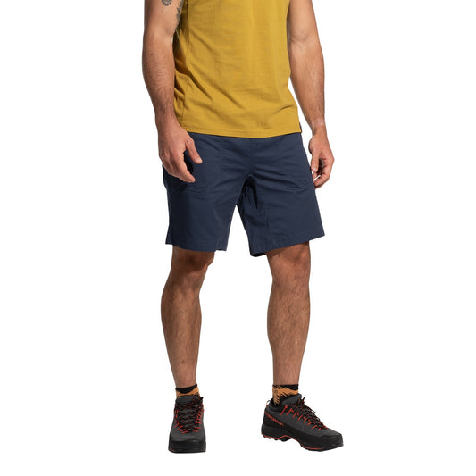 A man in a yellow T-shirt, La Sportiva Roots Shorts Men's (2025) in navy blue, and black hiking shoes with orange accents stands against a plain white background. His face is not visible.