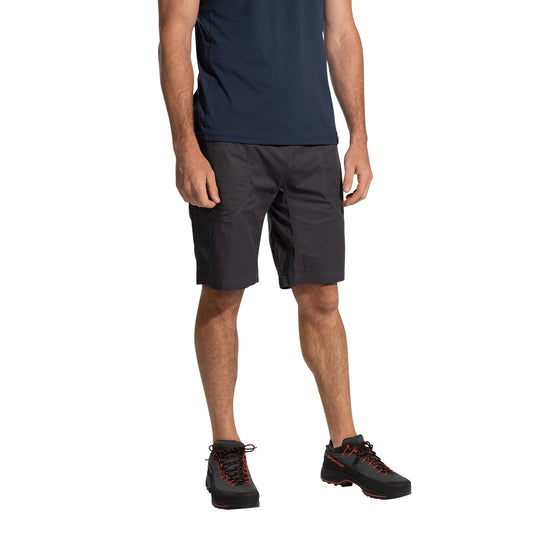 A man wearing La Sportiva Bolt Shorts Men's (2025) in navy, a matching navy t-shirt, and black hiking shoes with orange laces stands against a white background. His head is not visible in the image.