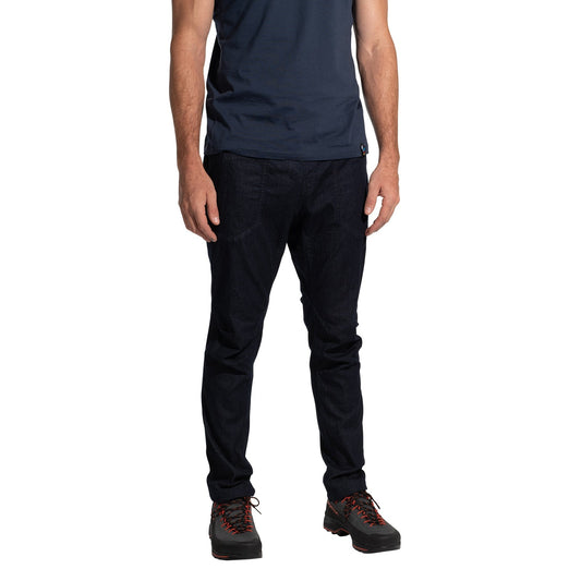 A man, head not visible, stands against a white background wearing a navy t-shirt, La Sportiva Cave Jeans Men's in dark blue, and black hiking shoes with red laces.