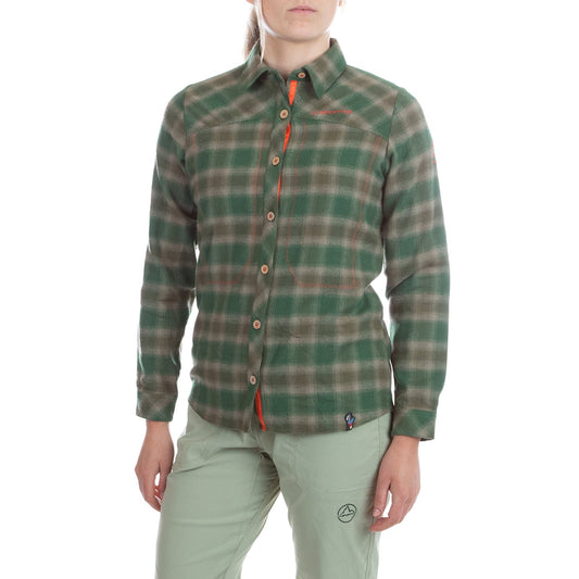 A person in a green and beige plaid La Sportiva Rambler Flannel Shirt Women's (2024) and light green pants stands against a white background, partially out of frame, showcasing their relaxed mountain style.