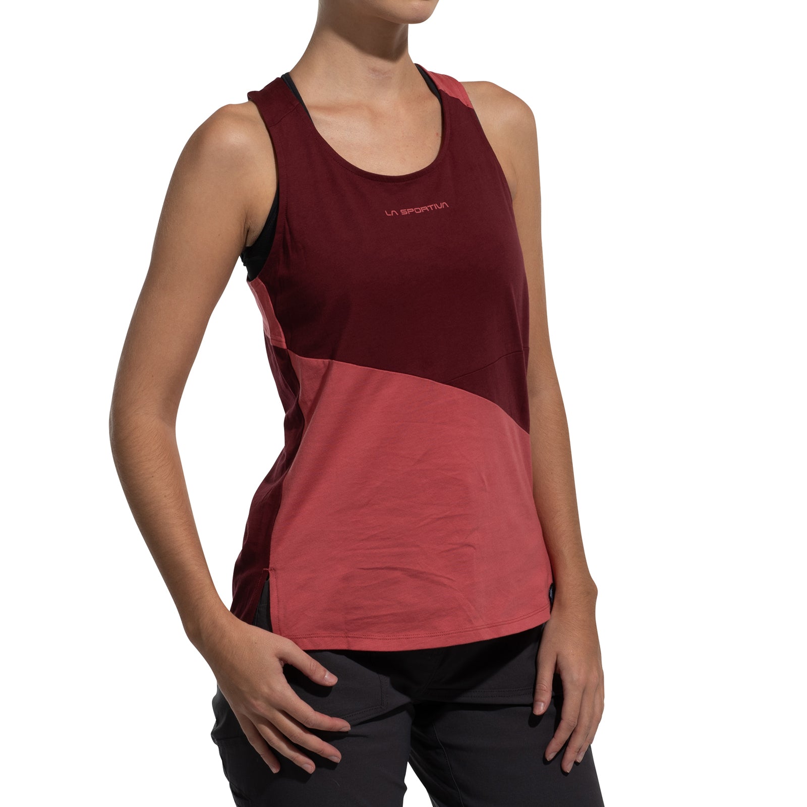 A woman in the La Sportiva Twist Tank Women's (2025)—a sleeveless maroon and pink organic cotton climbing top with logo—paired with dark pants, stands against a plain white background.