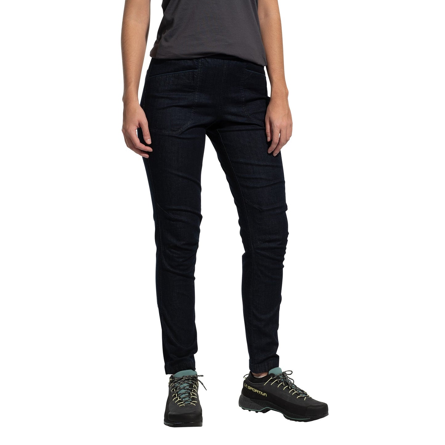 A person wearing La Sportiva Cave Jeans Women's in dark blue stands against a white background. The individual also wears a short-sleeve dark gray t-shirt and black hiking shoes with teal laces. The person's head is not visible.