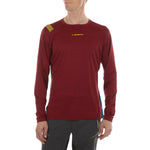 A person wears a La Sportiva Tour Long Sleeve Men's shirt in maroon with yellow logo, reflective details, and dark outdoor pants; the background is plain white.