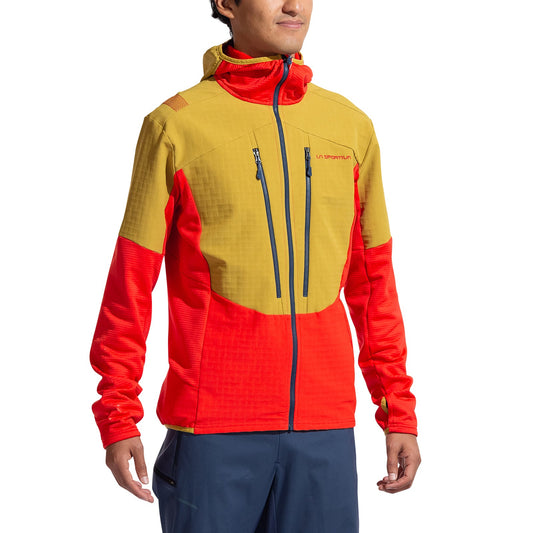 A person is wearing the La Sportiva Session Tech Hoody Men's, a two-tone recycled-material jacket with yellow shoulders and chest, bright red sleeves and torso, two vertical zippered chest pockets, and a high collar.
