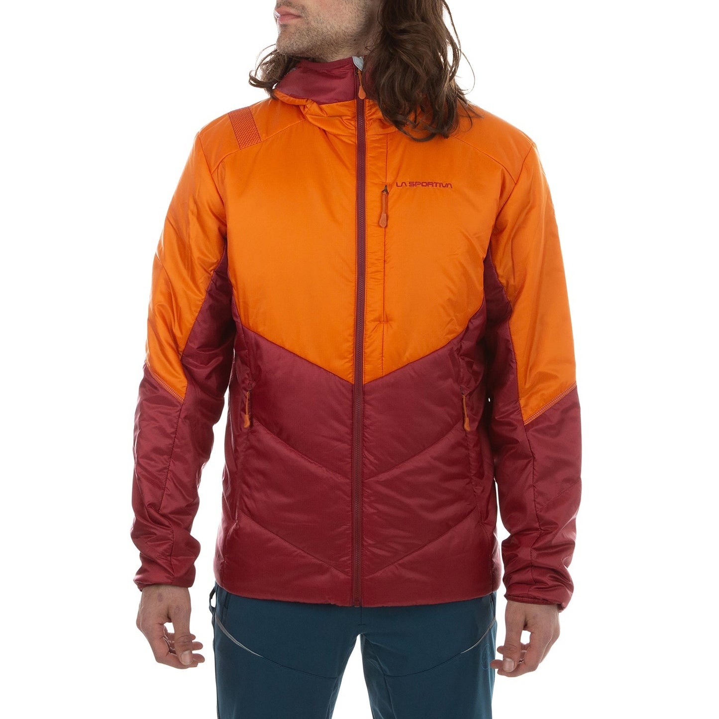 A man wears the La Sportiva Mythic Primaloft Jacket, an orange and red two-tone hooded style with PrimaLoft Silver Eco insulation, front zip closure, and two zippered pockets. He stands facing slightly left with arms relaxed at his sides.