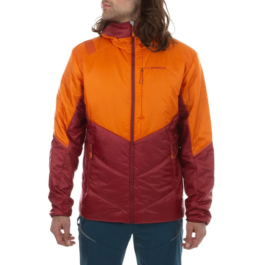 A man wears the La Sportiva Mythic Primaloft Jacket, an orange and red two-tone hooded style with PrimaLoft Silver Eco insulation, front zip closure, and two zippered pockets. He stands facing slightly left with arms relaxed at his sides.