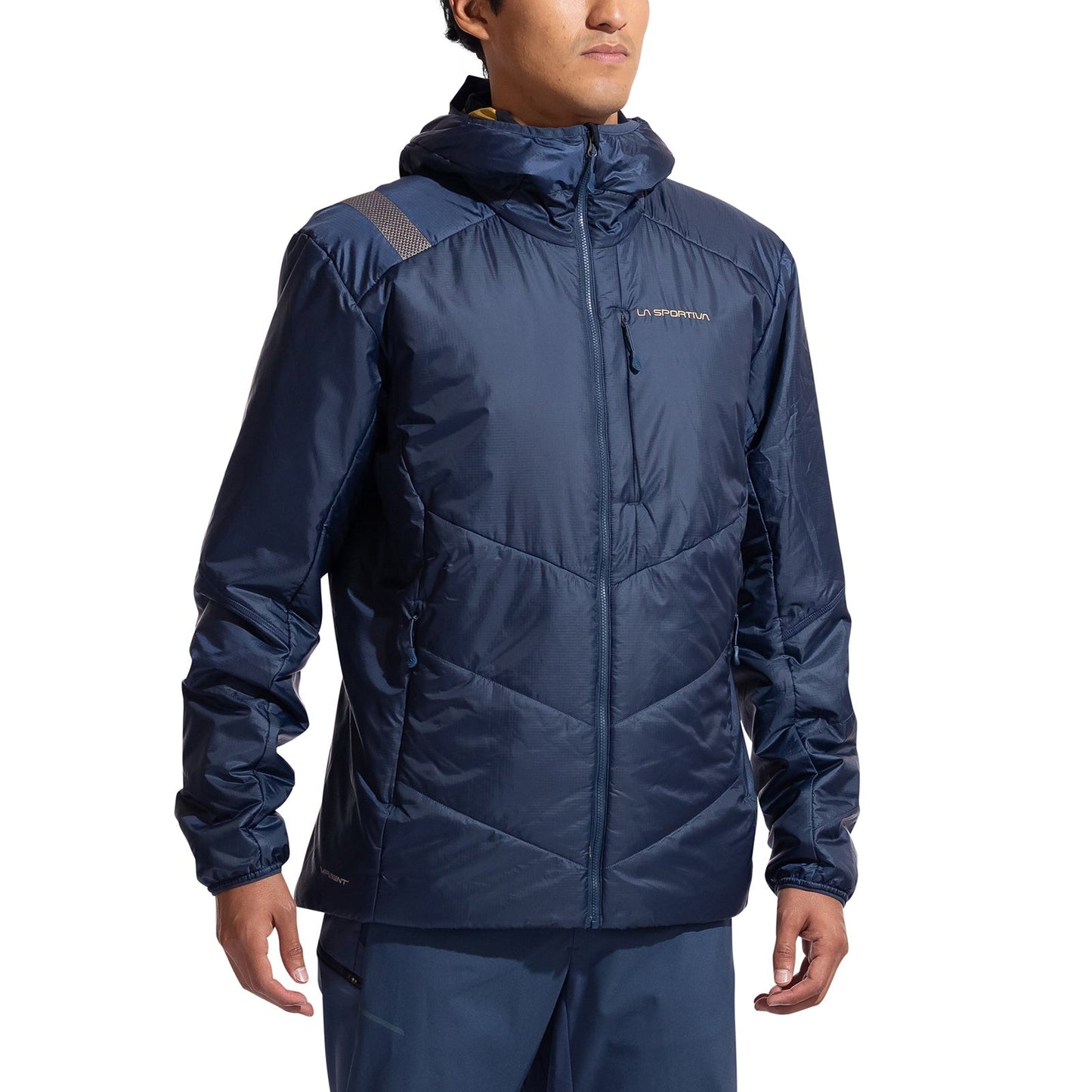 A person wears a navy blue La Sportiva Mythic Primaloft Jacket Men's with PrimaLoft Silver Eco insulation, quilted pattern, hood, zip-up front, and subtle chest logo, along with matching pants, standing against a plain white background.