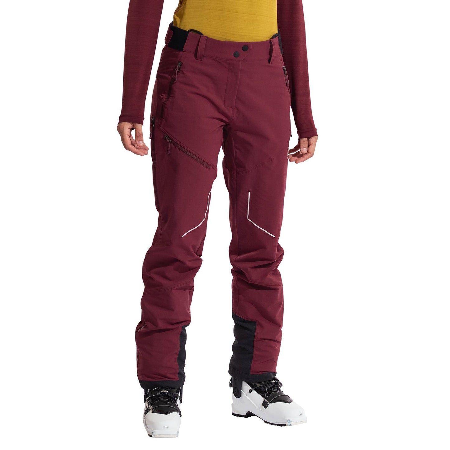 A person wears La Sportiva Excelsior Pants Women's—maroon breathable soft-shell pants with zippered pockets—plus black gaiters over white ski boots, a yellow top, and a red long-sleeve; ideal for ski-touring or mountaineering.