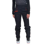 On voit une personne, de la taille aux pieds, portant un pantalon La Sportiva Crizzle EVO Shell Pants Women's avec des touches de rouge, un haut à manches longues noir et des chaussures de ski grises, sur fond blanc. Ce pantalon de protection pour femme de La Sportiva offre une protection exceptionnelle contre les intempéries.