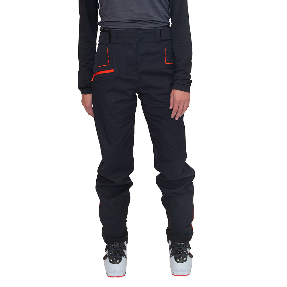 On voit une personne, de la taille aux pieds, portant un pantalon La Sportiva Crizzle EVO Shell Pants Women's avec des touches de rouge, un haut à manches longues noir et des chaussures de ski grises, sur fond blanc. Ce pantalon de protection pour femme de La Sportiva offre une protection exceptionnelle contre les intempéries.