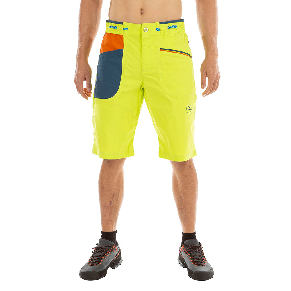 Une personne porte un short La Sportiva Belay Shorts Men's jaune vif avec des poches bleues et orange et une ceinture ajustable, avec des chaussettes noires et des chaussures de randonnée. La tête et les bras de la personne sont coupés dans l'image.
