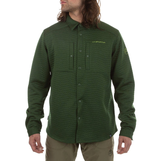 A person wears the La Sportiva Spacer Shirt Men's in olive green, a long-sleeve top made with recycled materials and featuring the La Sportiva logo on the chest and sleeve, standing with arms relaxed and head slightly turned.