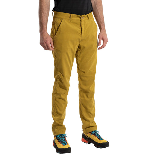 A person wears La Sportiva Setter Pants Men's in mustard yellow corduroy, a black shirt, and colorful hiking shoes, standing hands relaxed against a white background. Face not visible. Ideal cold weather climbing gear.